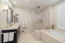 Bathroom features Crema Marfil marble on floor, shower and tub surround.