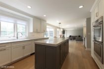 Kitchen features gray island with white surrounding cabinets.
