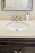 Bathroom features Crema Marfil Mable Slab countertop with under mount sink.