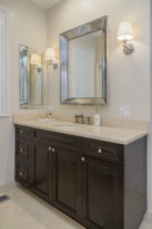 Bathroom features Custom Cabinetry in dark wood. Crema Marfil Marble slab countertop with 4 inch backsplash.